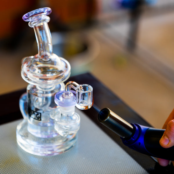 the dung recycler dab rig being heated up with a jet torch on top of a dab mat